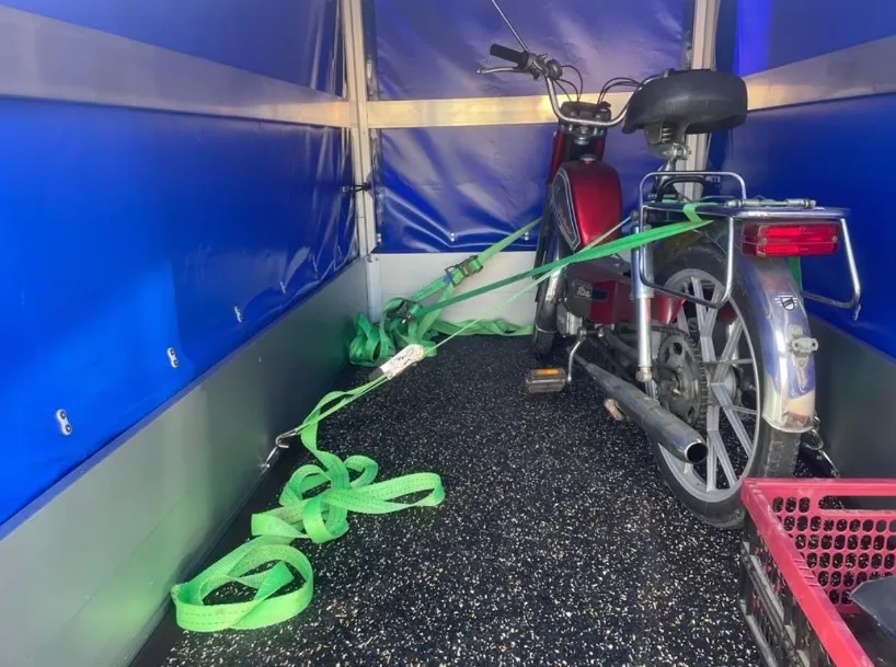 Motorrad mit grünen Spanngurten an den Ankerpunkten im Anhänger gesichert