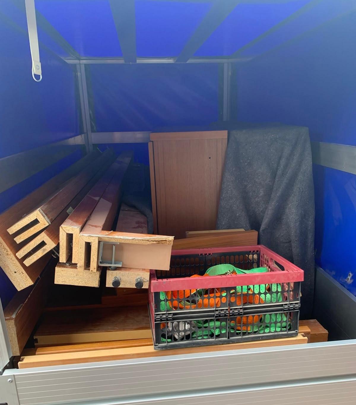 Mit Holz, Material und Spanngurten beladener Anhänger – bereit für die Entsorgungsfahrt